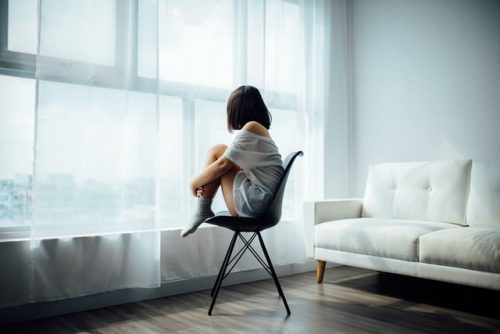 A girl sitting on a chair, running her thoughts. That is the first step of what is cognitive behavioral therapy about.